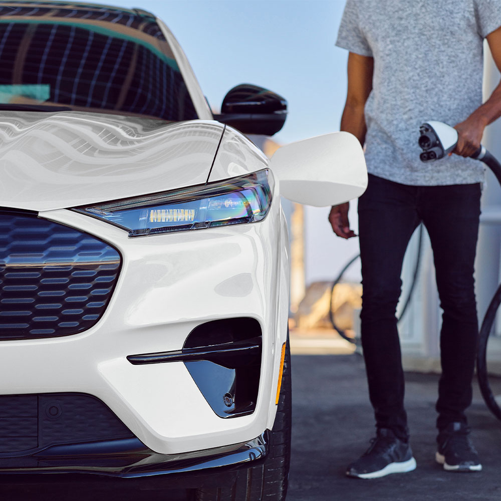 White Mustang Mach-E getting plugged into a charging station